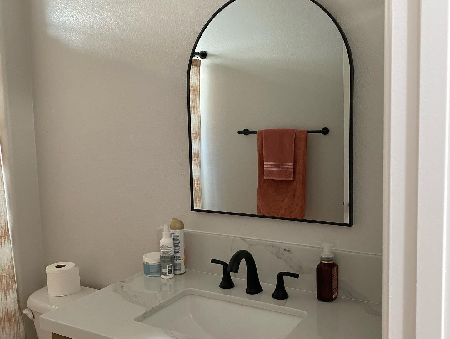 R&B project: arched black mirror over a white sink with a black faucet