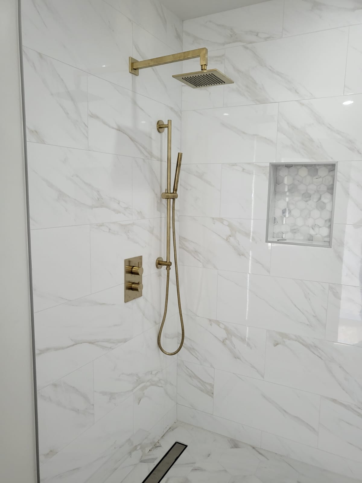 R&B project: marble-look shower with brushed-gold fixtures, a niche and a linear drain