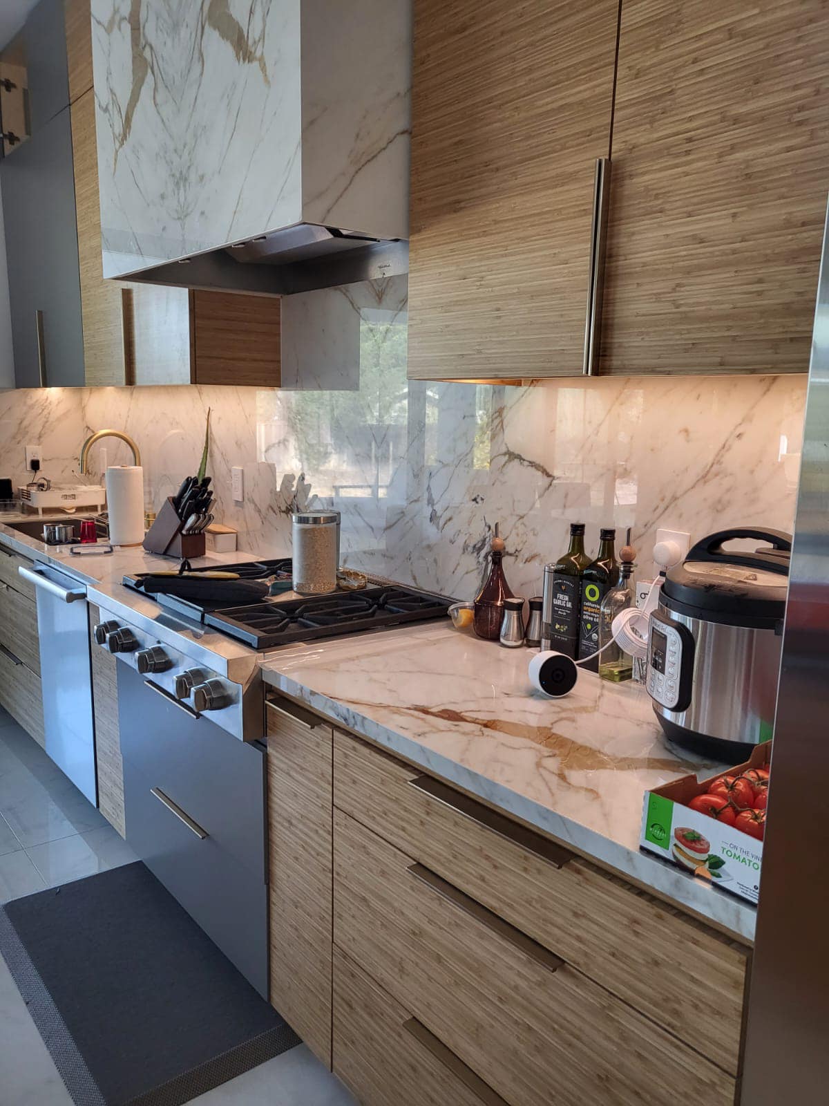 R&B project: wood flat-panel cabinets with a marble-look slab backsplash and hood over a range