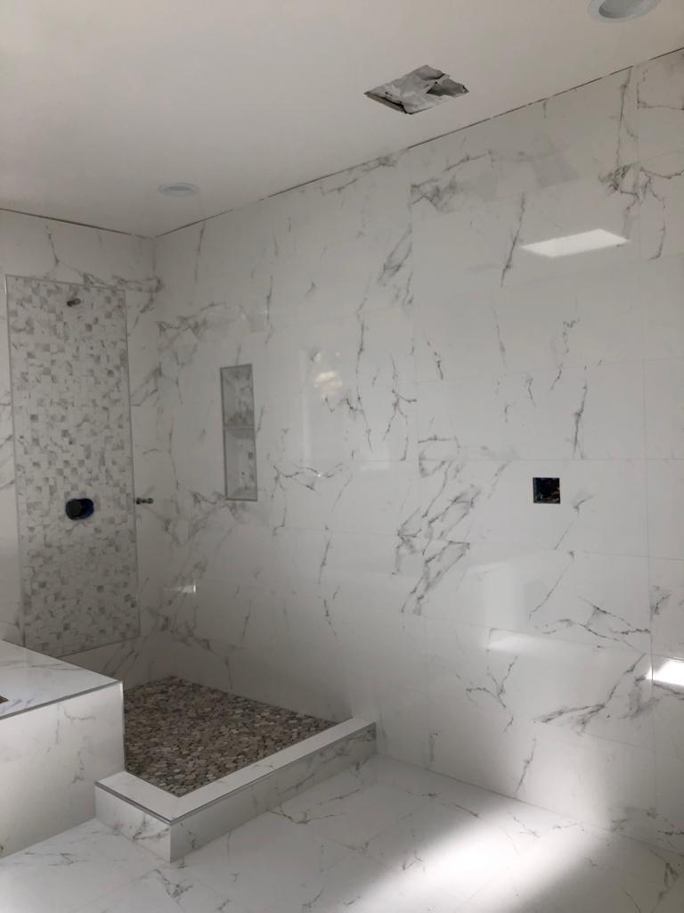 R&B project: marble-look walk-in shower with a pebble floor and black fixtures