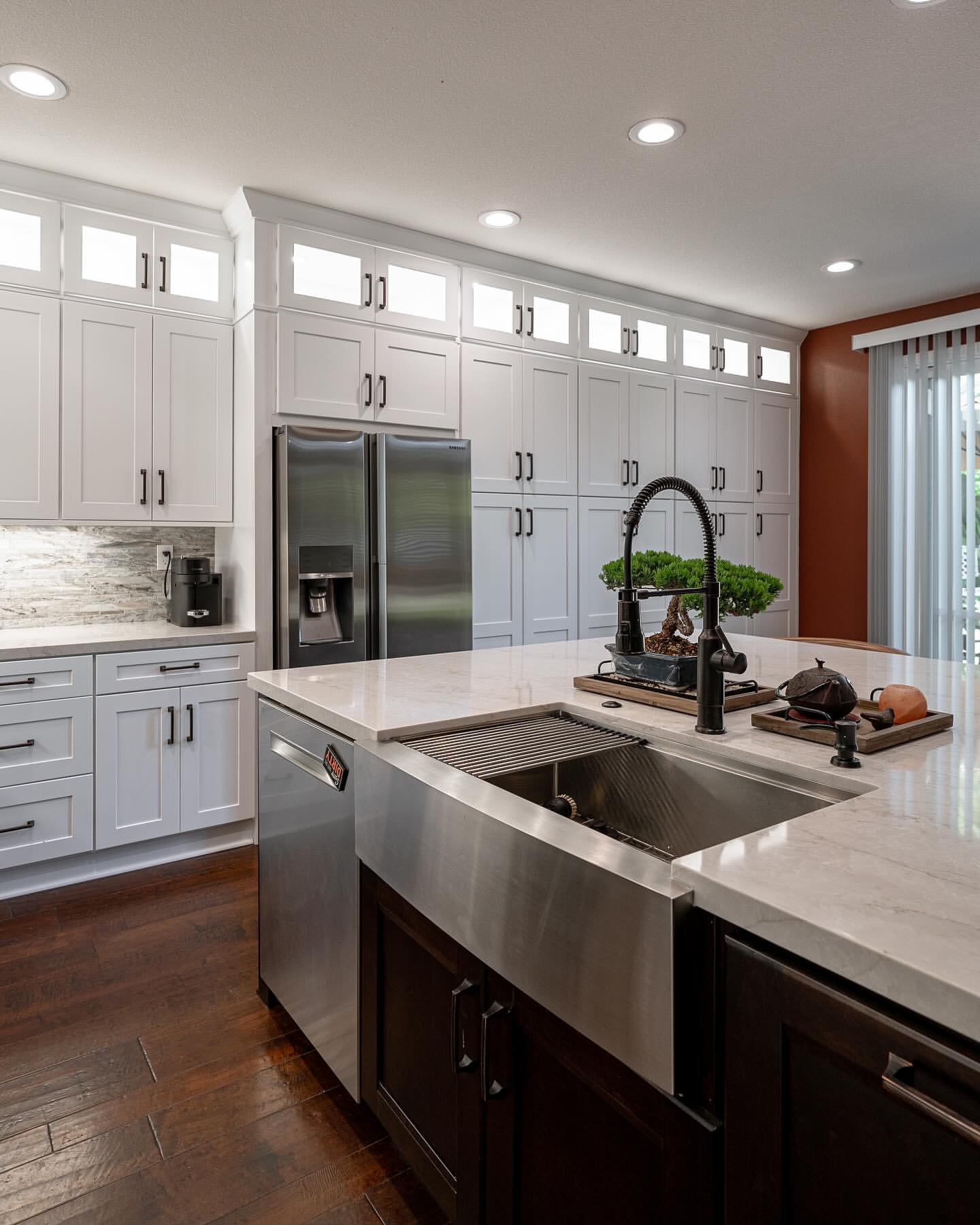 R&B project: white kitchen with glass transom uppers and a stainless farmhouse sink in a dark island