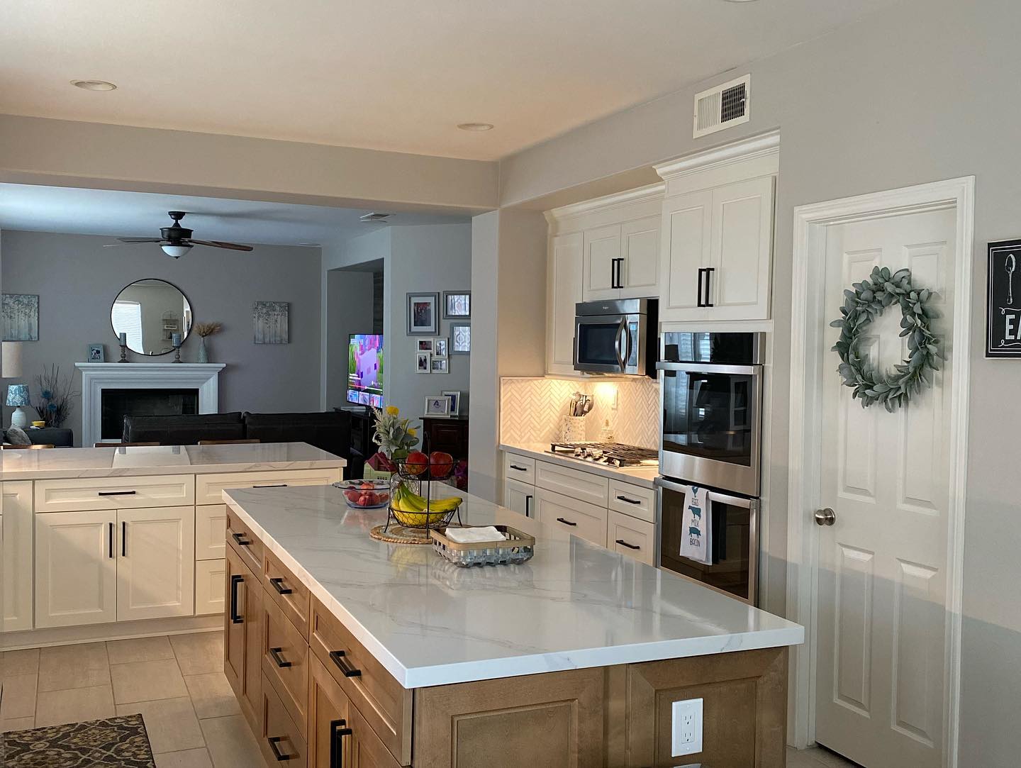 R&B project: white kitchen with a stained wood island facing stacked wall ovens