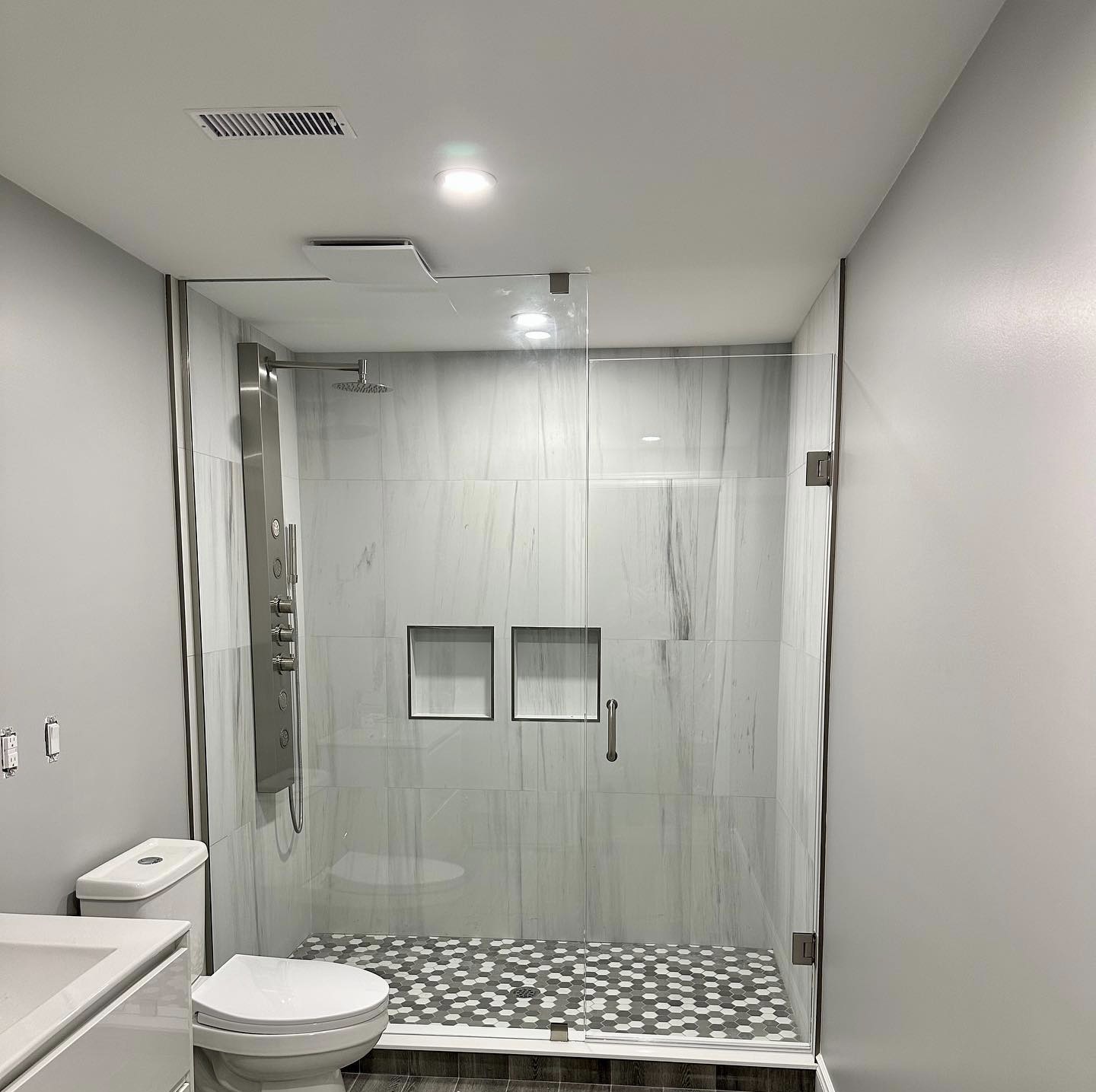 R&B project: long shower with a glass panel, wall niches and a pebble floor