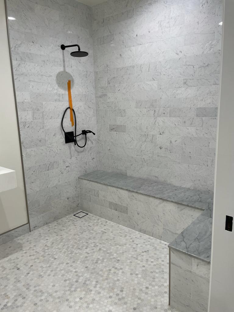 R&B project: gray stone shower with a bench, black fixtures and a hexagon tile floor