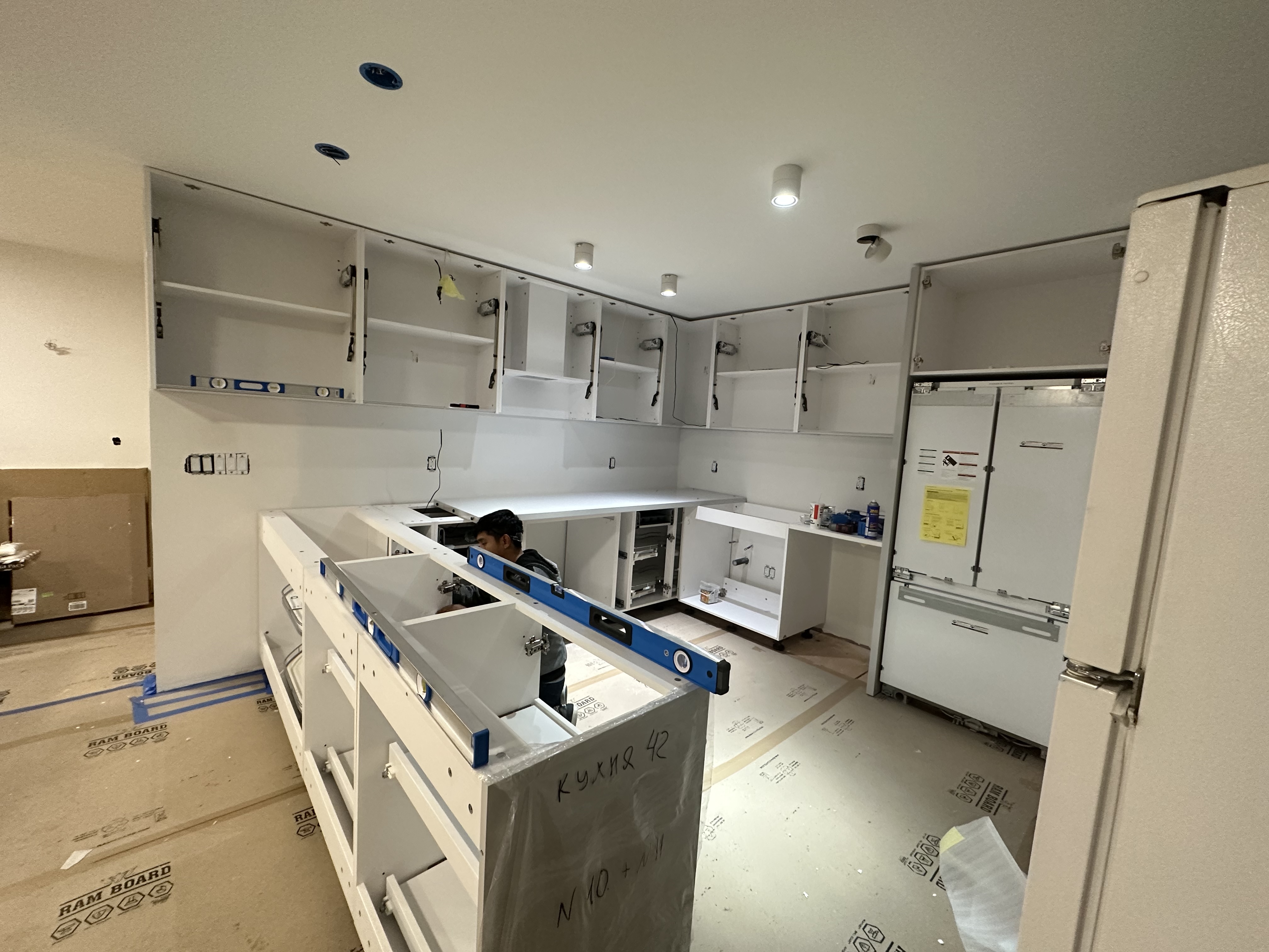 R&B project: kitchen cabinets being installed with protection on the floor