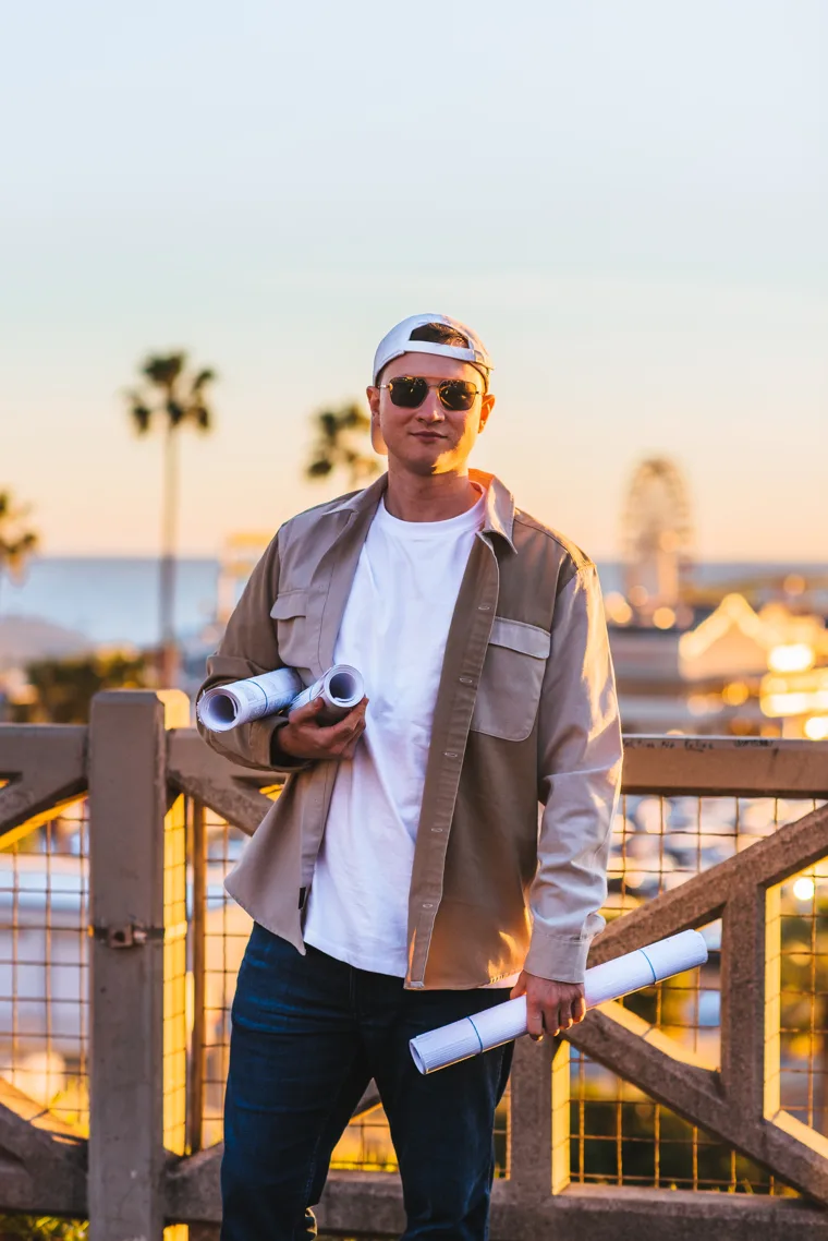 Andrew Atamaniuk, CEO of Ataman Studio Architects, holding rolled architectural drawings at sunset